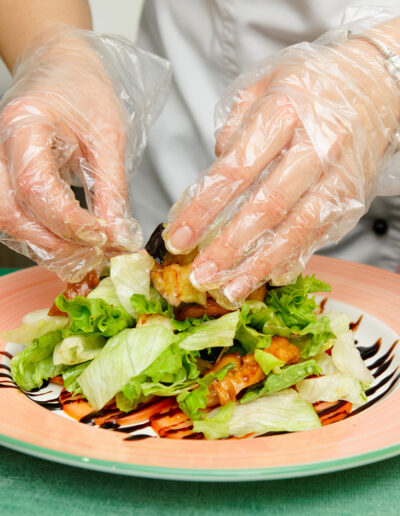 Food worker wearing personal protective equipment while handling raw food
